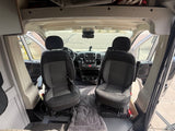 RV rental: Interior view of a camper van's front cabin with swivel seats & dashboard, ready for journeys.
