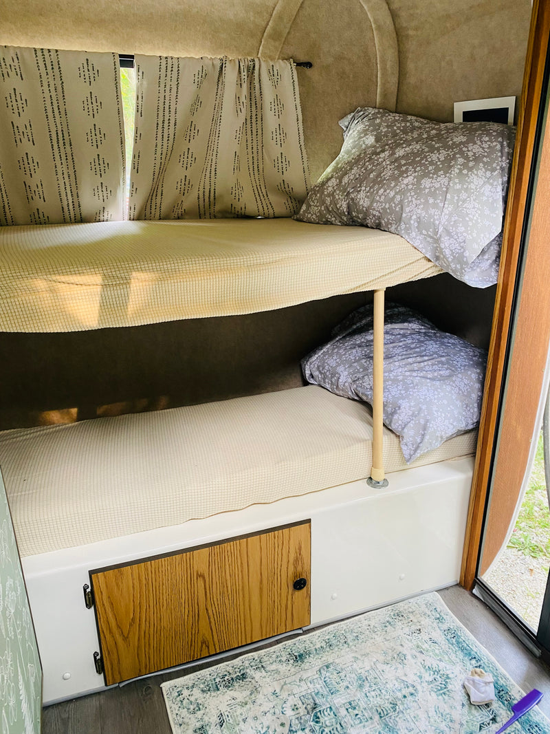 Bunk beds inside an RV rental, offering a cozy sleep space with floral pillows & patterned curtains. — photo 10