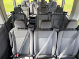 Interior of an RV rental van featuring multiple rows of grey passenger seats with safety belts, ideal for group trips.