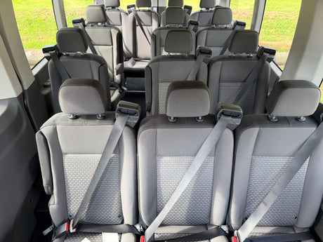 Interior of an RV rental van featuring multiple rows of grey passenger seats with safety belts, ideal for group trips.