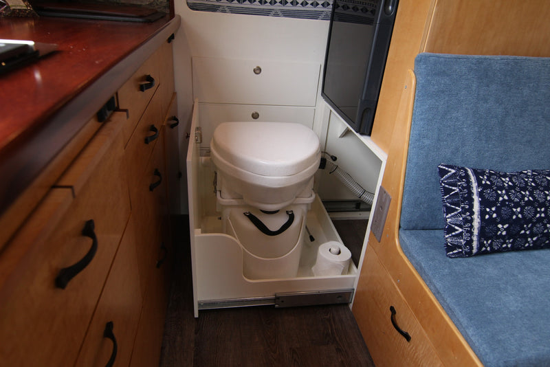 Compact RV rental interior reveals a clever pull-out toilet, wooden cabinetry, and blue seating for efficient space use. — photo 10