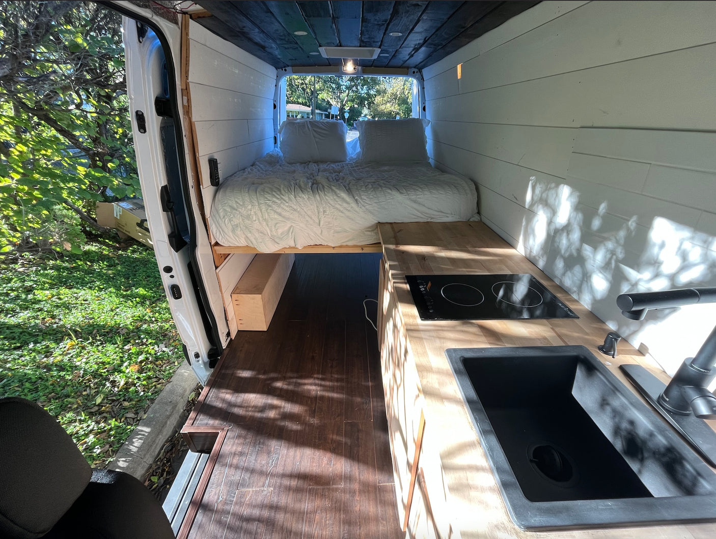 Experience van life! This rv rental showcases a beautifully converted interior with bed, kitchen, and warm lighting.