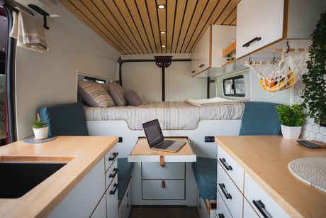 This cozy RV rental features a full bed, custom kitchen, and a convertible dinette with a laptop for travel work.