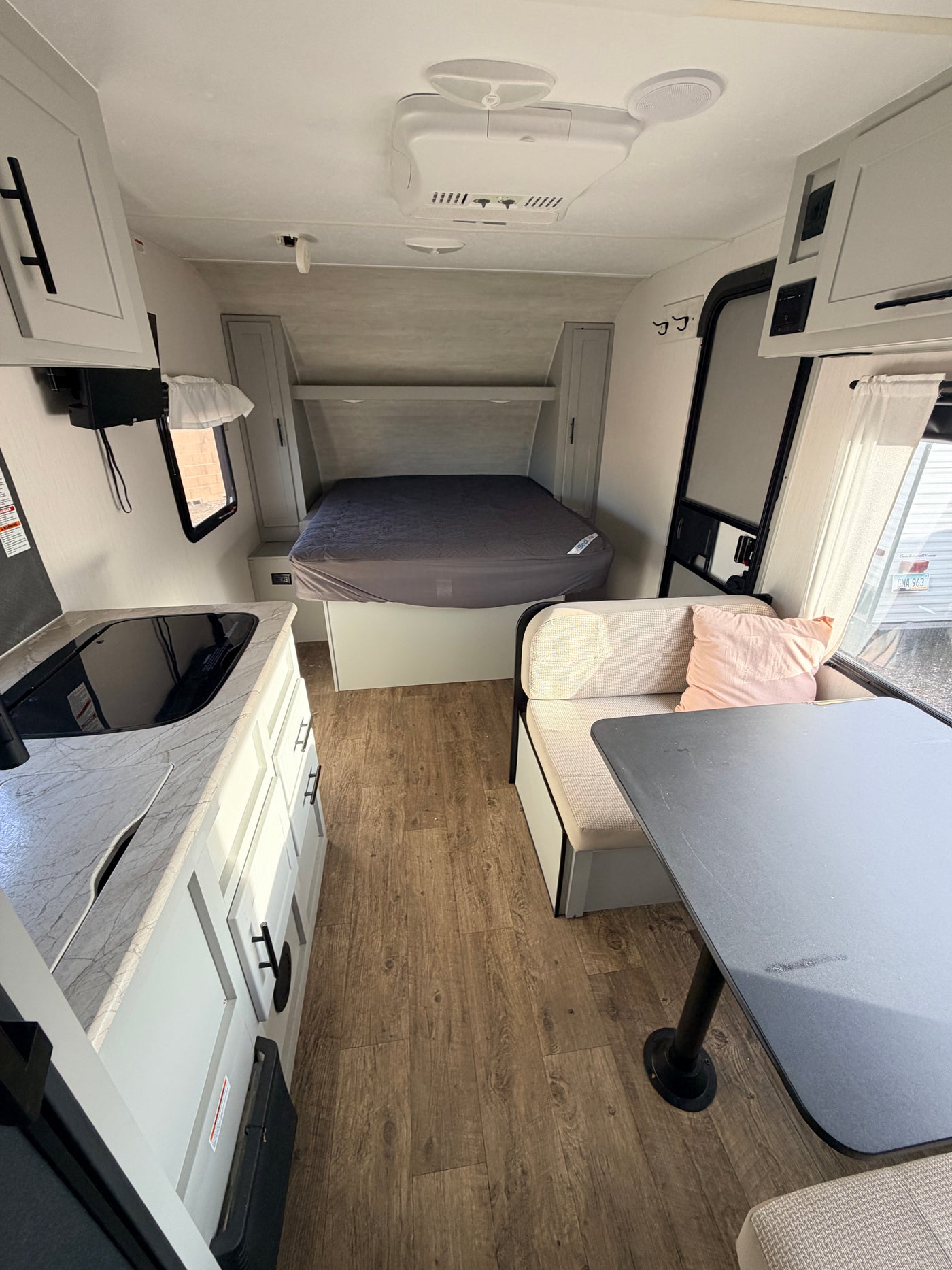 Spacious RV rental interior featuring a comfy bed, kitchen, and dinette with light wood floors. Modern and functional. — photo 11