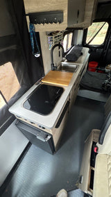 RV rental interior: A modern camper van kitchen with a sink, cooktop, fridge, and clever storage solutions.