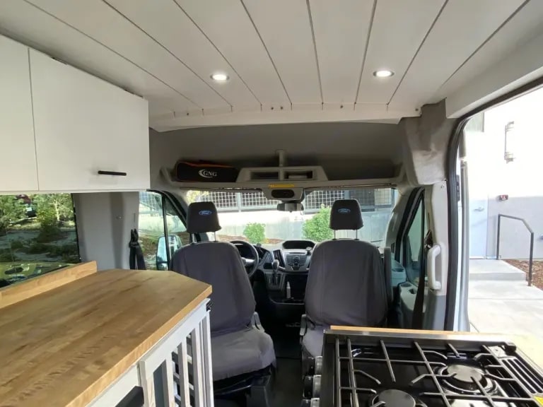RV rental: Inside a well-equipped camper van, showcasing the kitchenette, front seats, and overhead storage. — photo 6
