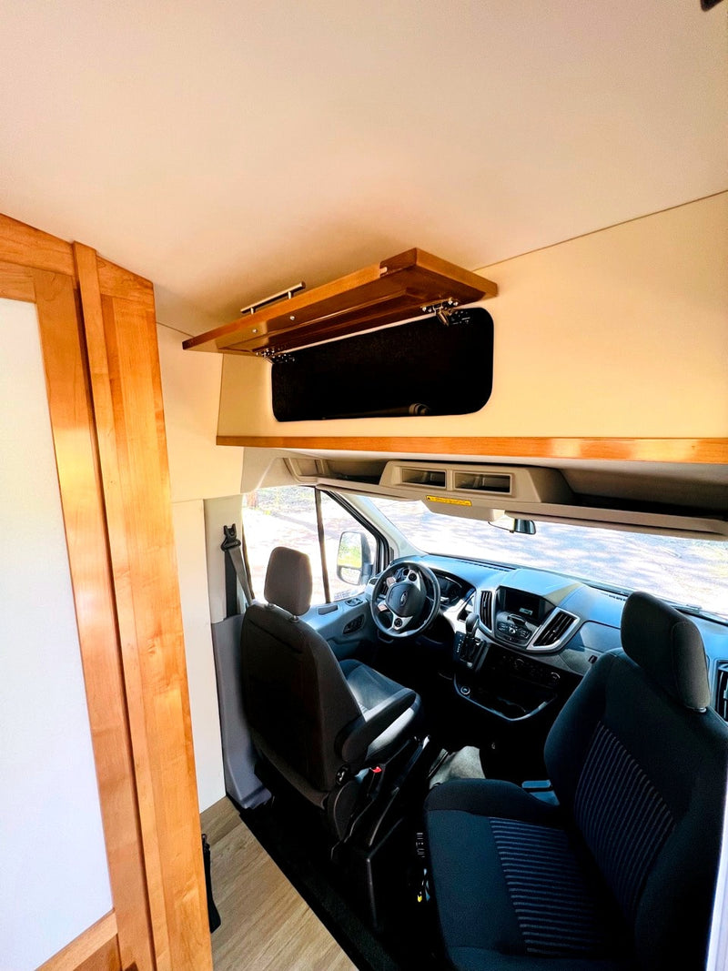 RV rental interior view: front cabin with seats & dashboard, plus an open wooden overhead storage cabinet. — photo 7