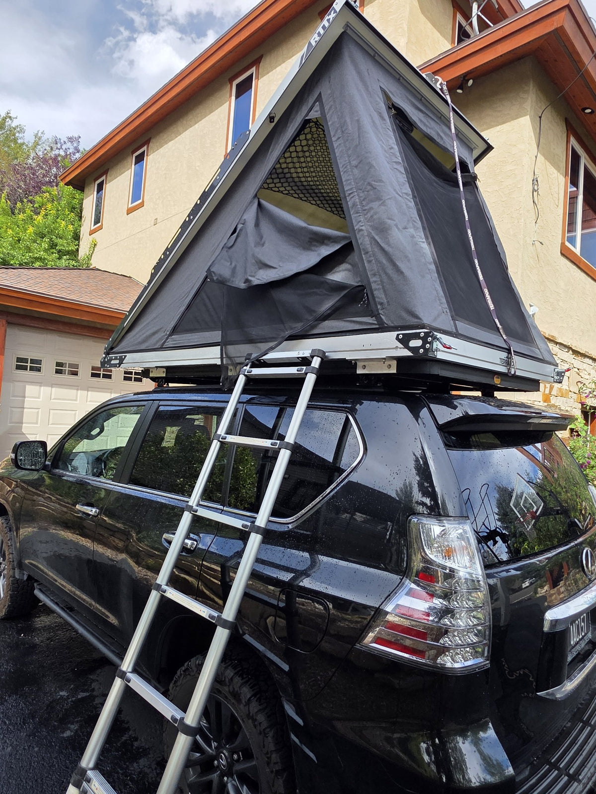Terrapod RTTx XL opened with the telescoping aluminium ladder extended down to the ground at the rear of the vehicle, showing the rainfly and the RTTx branding on the shell end cap — photo 9