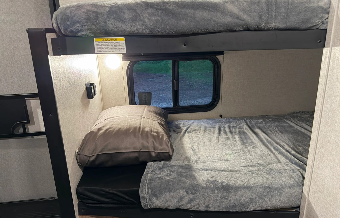  is parked in a forest campsite next to a campfire and pickup.|Side view of a Coleman travel trailer RV rental — photo 8