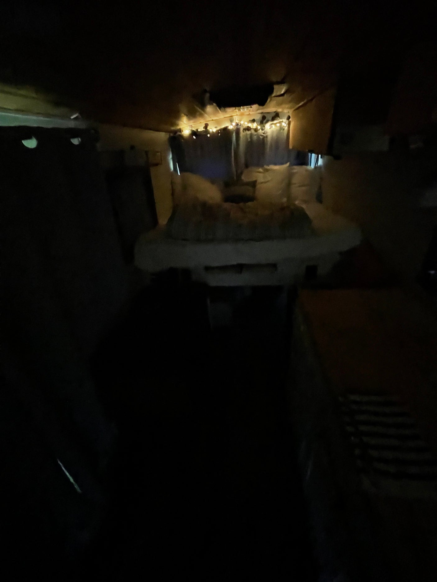 Dimly lit RV rental interior. String lights illuminate a narrow, cozy living space, ideal for travel.