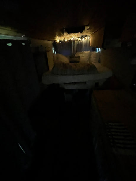 Dimly lit RV rental interior. String lights illuminate a narrow, cozy living space, ideal for travel.