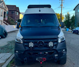 Front view of a rugged, customized Mercedes-Benz Sprinter camper van for rv rental. Features off-road bumper, winch, and roof lights.