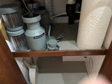 Compact kitchen storage in an RV rental, featuring a Beast blender, paper towels, and under-sink plumbing.
