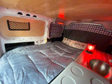 Comfortable rv rental interior featuring a cozy bed, plaid details, ambient red lighting, and a small sink.