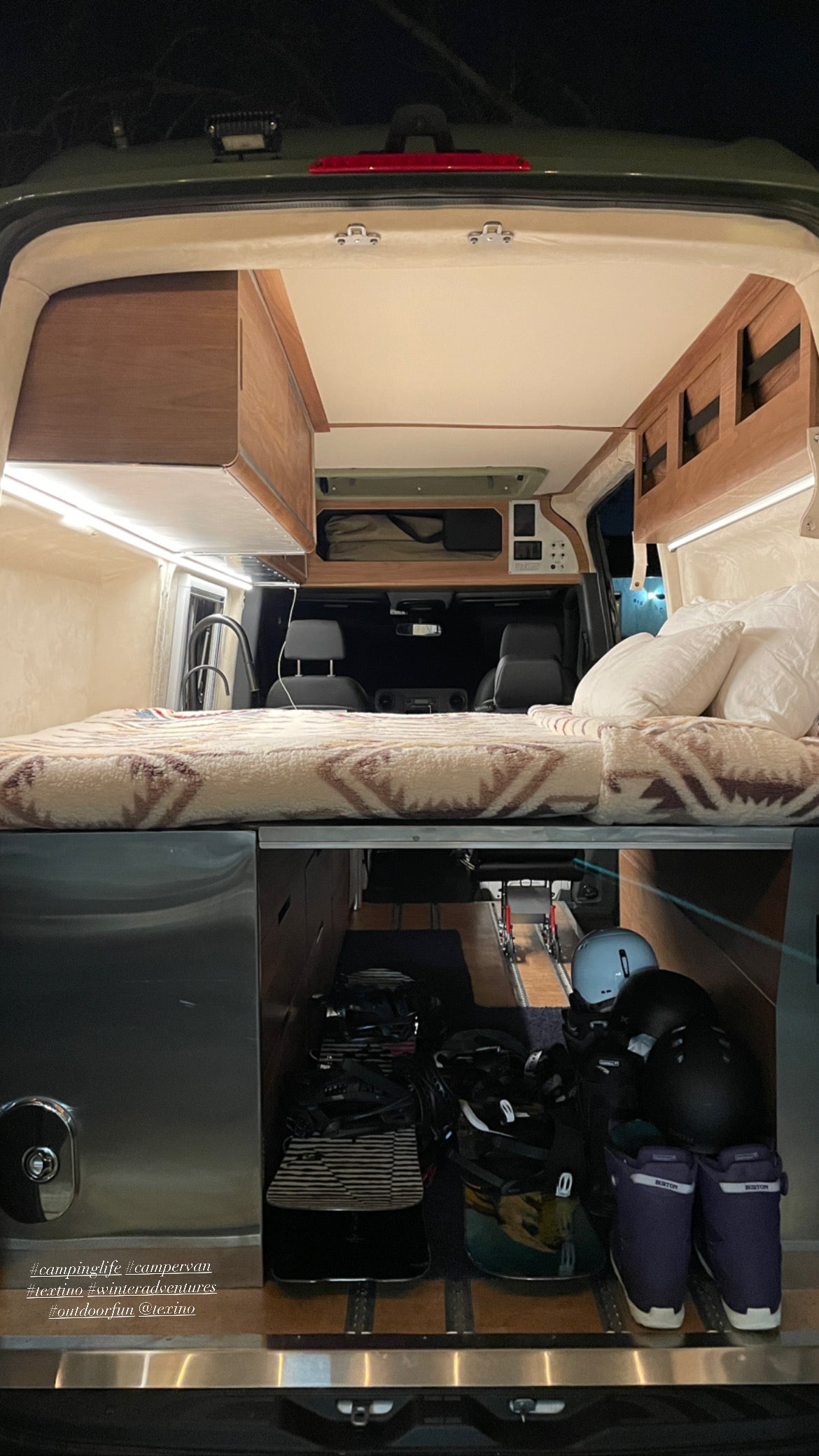 This spacious rv rental camper van features a bed over organized gear storage, ideal for winter adventures.