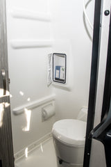 RV rental bathroom: This bright, white wet bath features a toilet, shower, and recessed storage for toiletries.