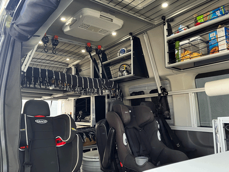 Inside a custom **RV rental**: child car seats, an elevated bed, and a modular storage system. Perfect for family adventures.