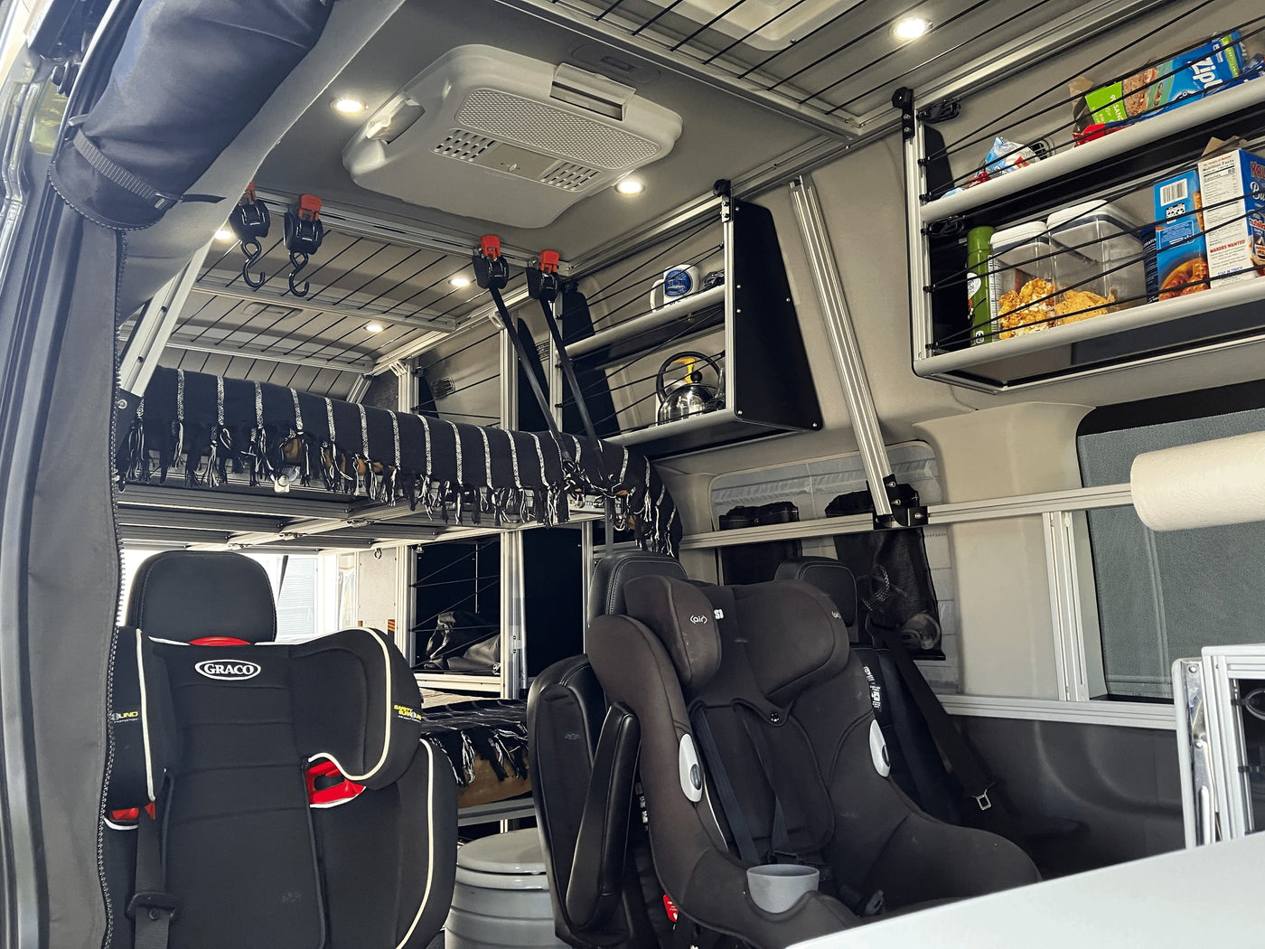 Inside a custom **RV rental**: child car seats, an elevated bed, and a modular storage system. Perfect for family adventures. — photo 13