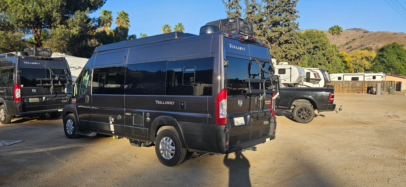 Two Ram ProMaster Tellaro camper vans, possibly rv rental units, are parked in a sunny RV park.