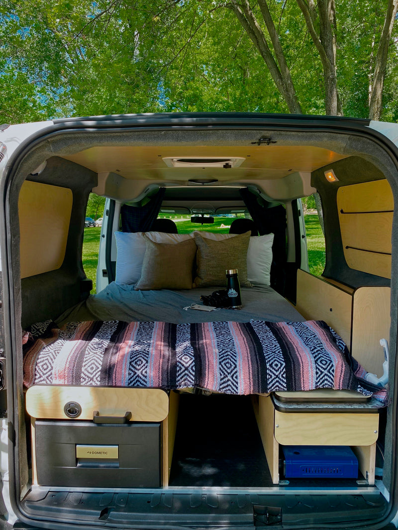 Inviting RV rental camper van interior with cozy bed, Dometic fridge, and portable stove setup. — photo 15