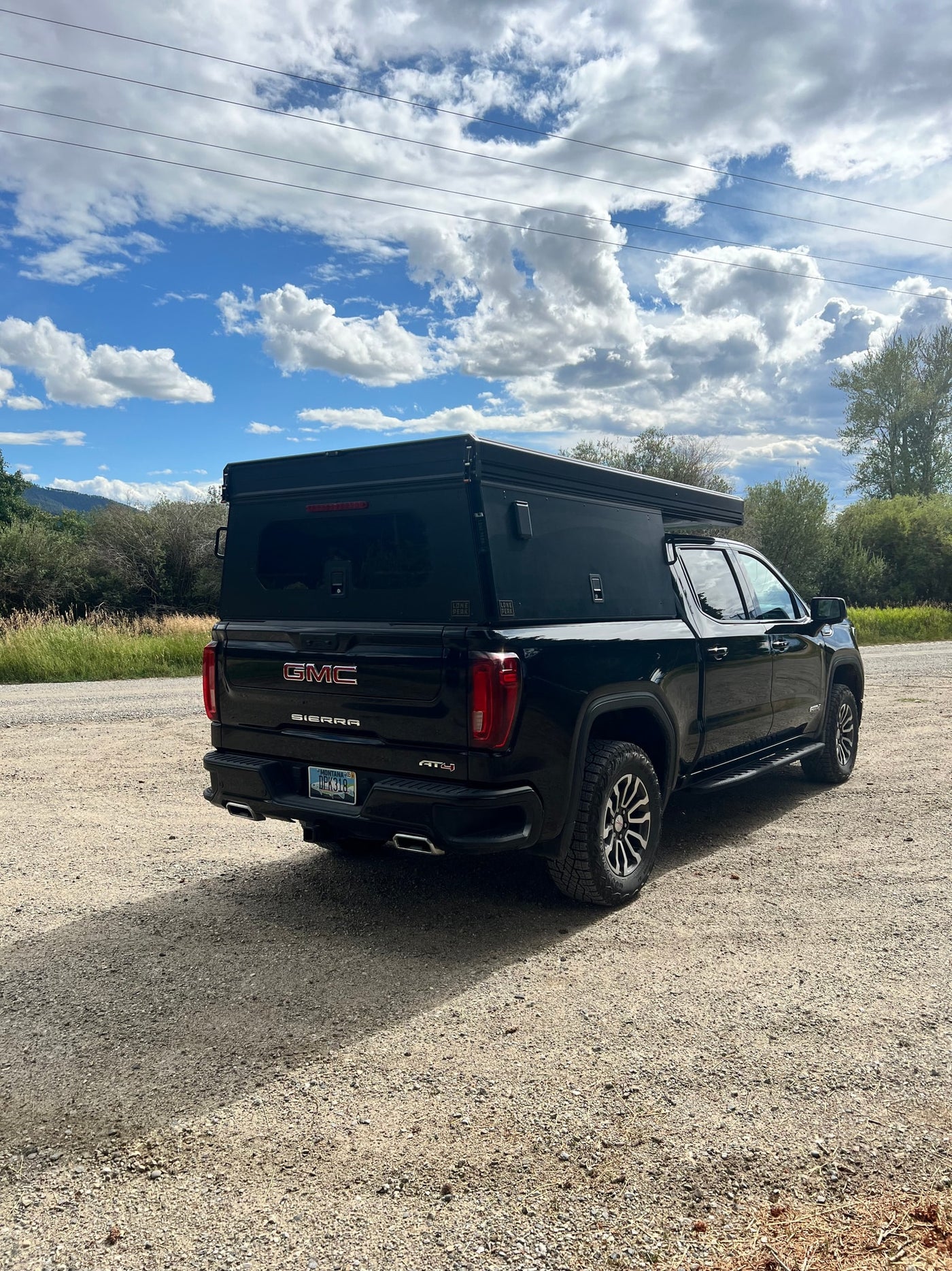 Black GMC Sierra truck with a Lone Peak truck bed camper, ideal for an RV rental or overlanding. — photo 4