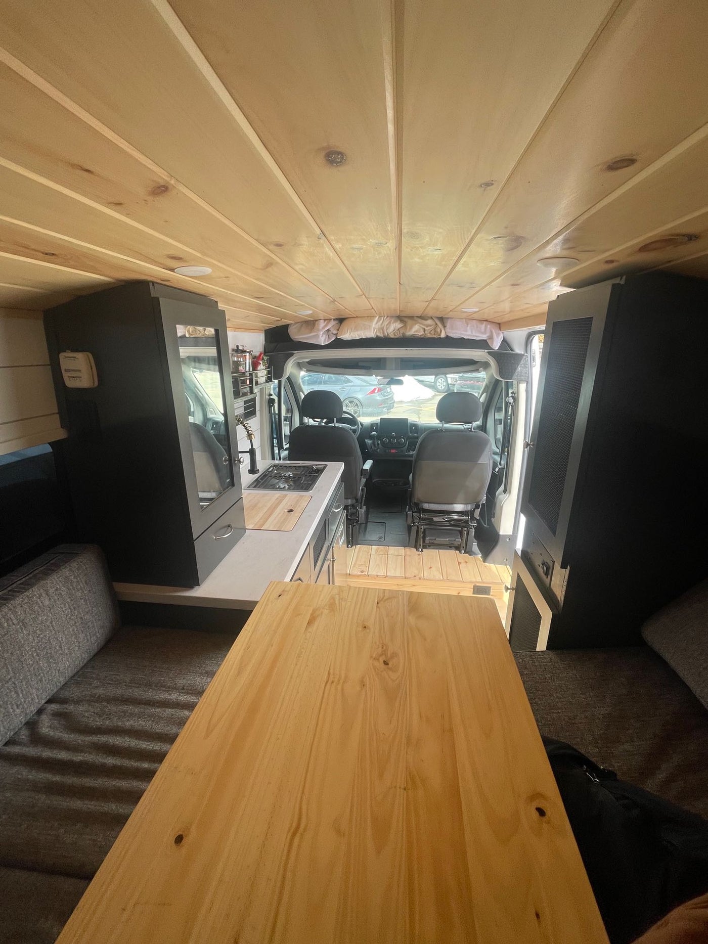  and cabinet storage.|This cozy camper van interior for RV rental boasts a wooden ceiling — photo 8