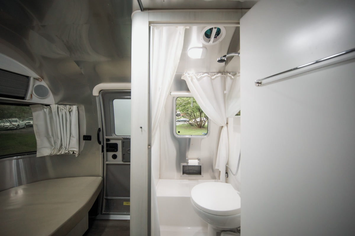 Inside a bright rv rental: compact bathroom with shower/toilet, adjacent to seating area and window views. — photo 3