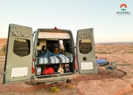 RV rental adventure: Couple cozy in their campervan with open doors, enjoying the scenic desert outdoors.