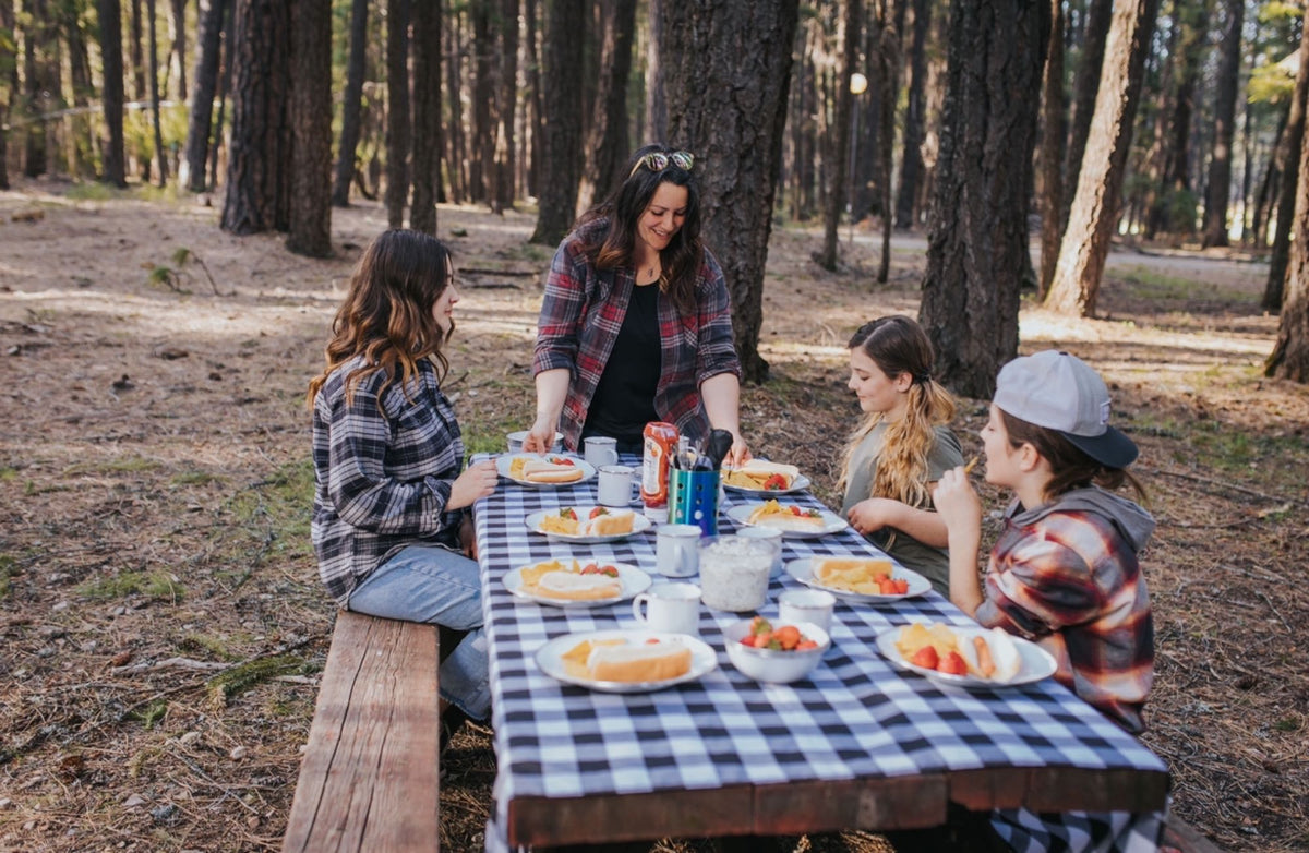  with hot dogs and snacks on a checkered table.|A vibrant campsite setup under a large canopy in a forest — photo 9