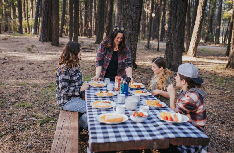  with hot dogs and snacks on a checkered table.|A vibrant campsite setup under a large canopy in a forest — photo 9