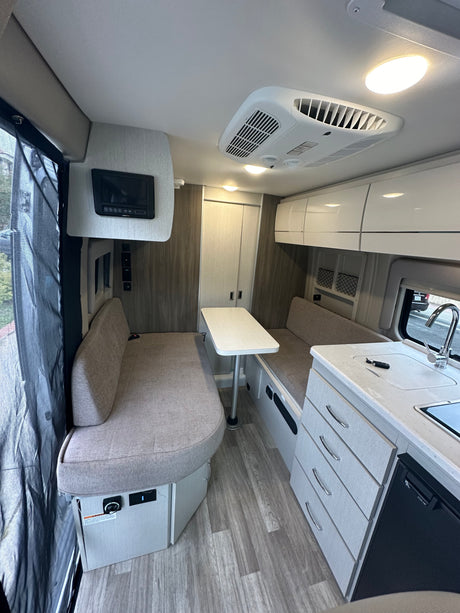 Bright RV rental interior showing a dinette, kitchen, and ample storage for comfortable travel and camping.