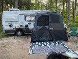 RV rental at a wooded campsite featuring an outdoor kitchen, Joolca privacy tent, and pet mats for a furry friend.