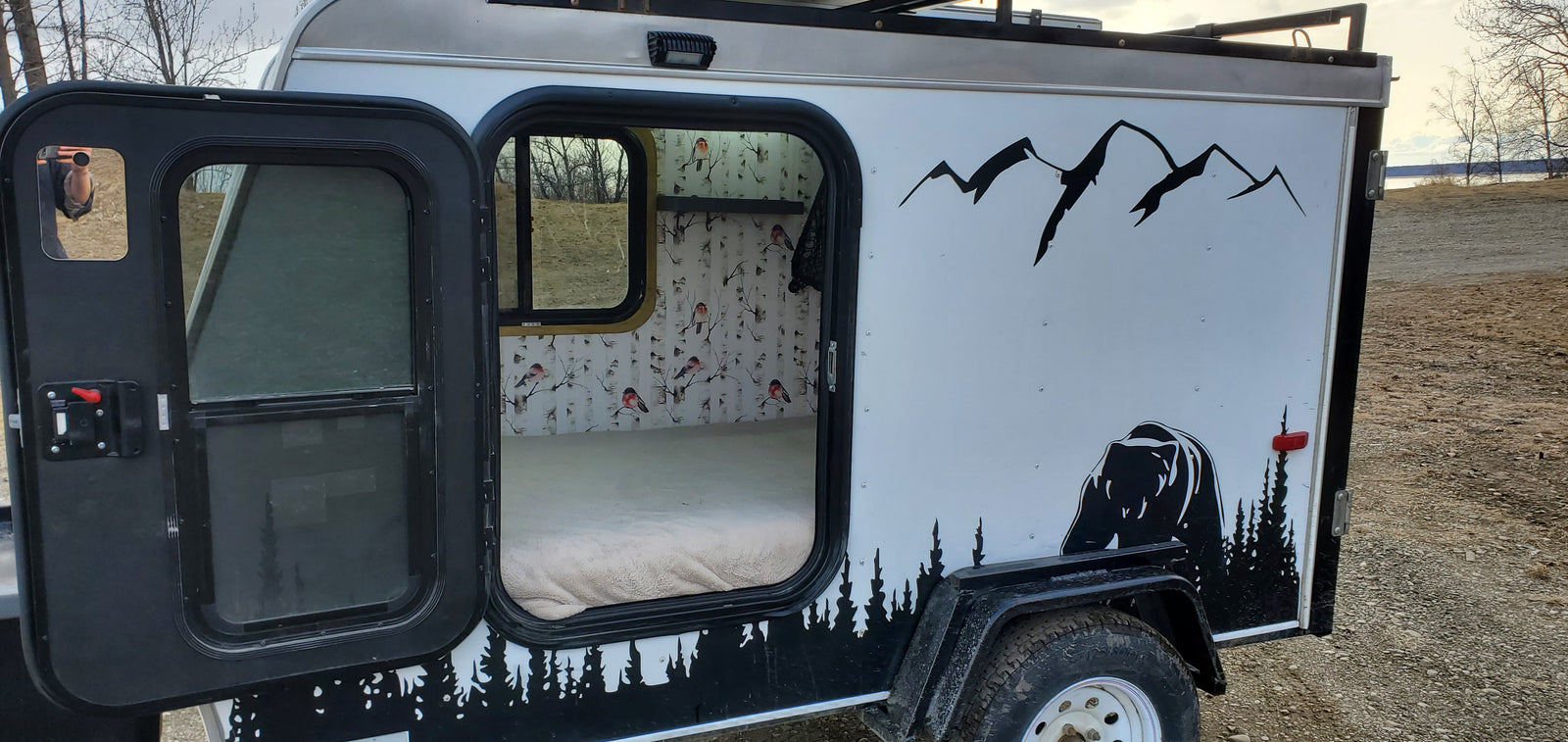 Cozy RV rental camper: custom bear and mountain exterior, warm interior with birch tree & bird wallpaper. Perfect for outdoor adventure.