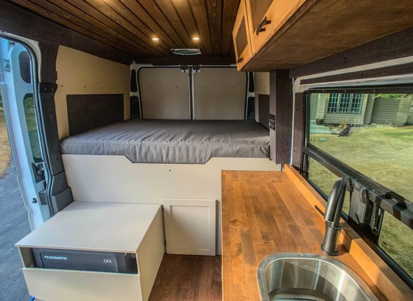 Inside this RV rental: a built-in bed, Dometic fridge, and wood kitchen counter. Ideal camper van setup. — photo 5