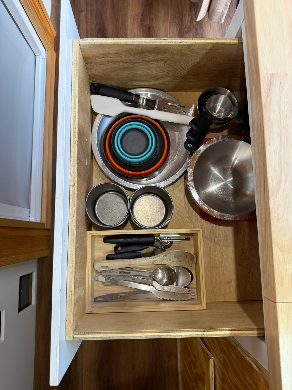 This RV rental kitchen drawer features neatly organized compact cookware, utensils, measuring cups, and foldable bowls for efficient use. — photo 10