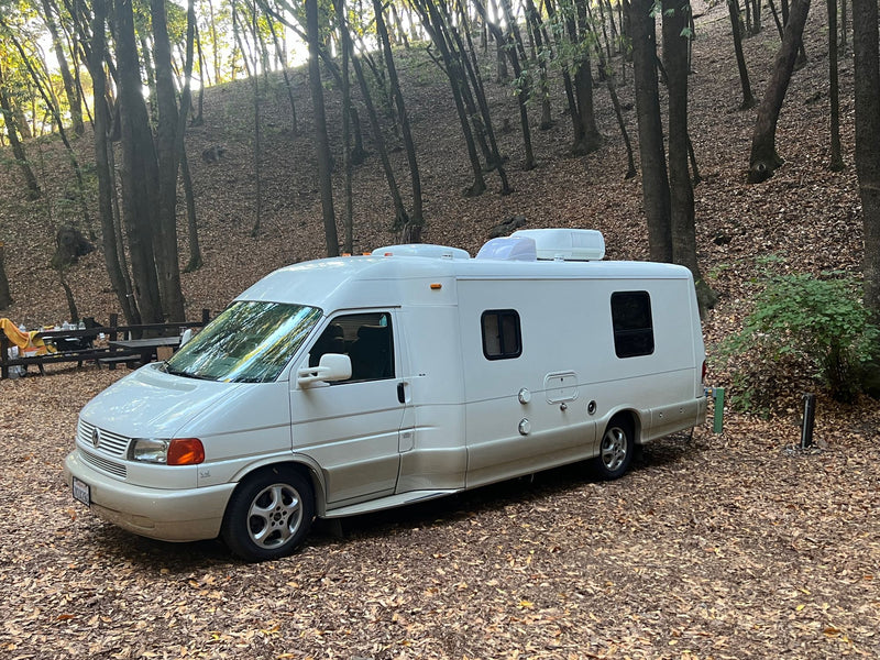 White rv rental camper van parked on autumn leaves in a peaceful — photo 1