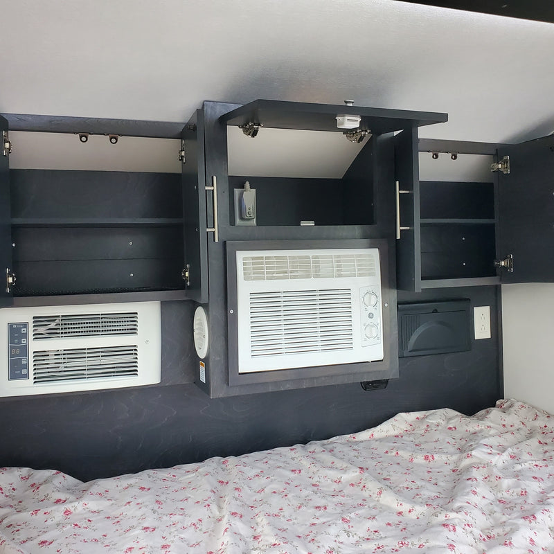 RV rental: Cozy sleeping area with overhead storage, dual AC units, and floral bedding. — photo 9