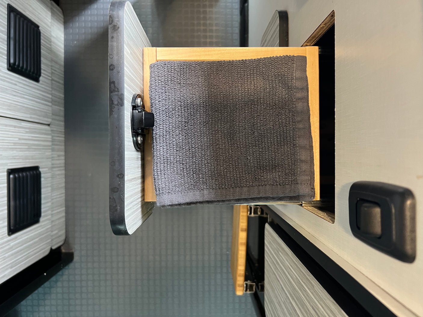 RV rental interior: Open drawer with a grey towel, showing practical storage inside this camper van.
