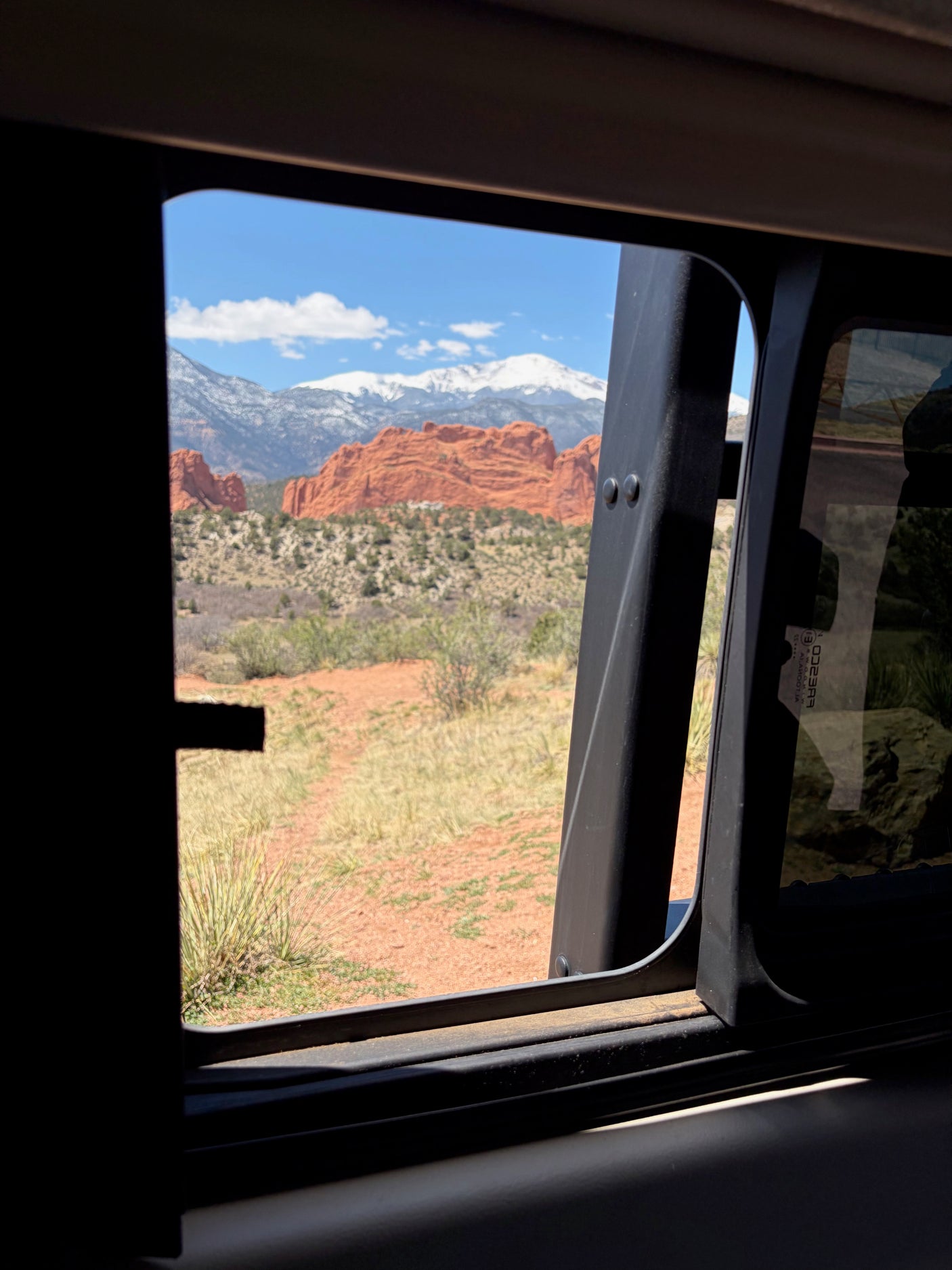 Stunning red rocks and snow-capped mountains seen from an RV rental window. Your next scenic adventure awaits!
