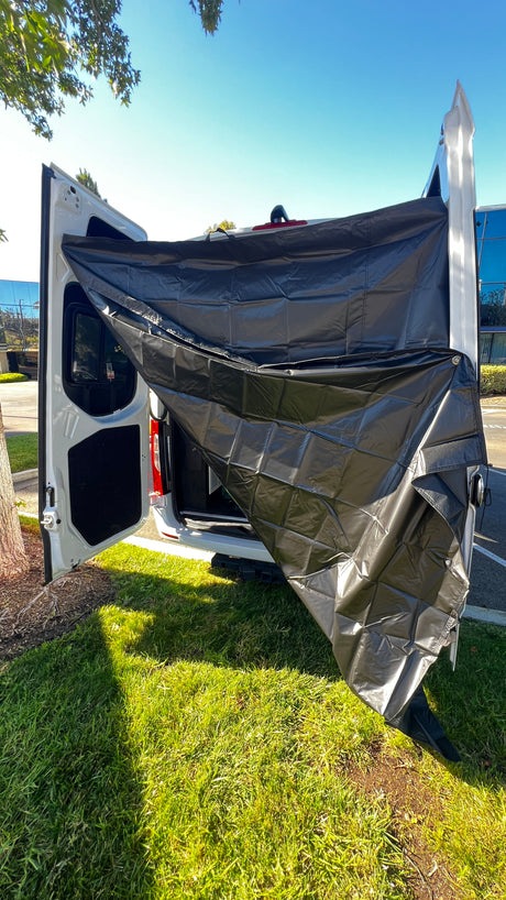 RV rental camper van with black privacy screen extended from open rear doors, parked on grass for outdoor use.