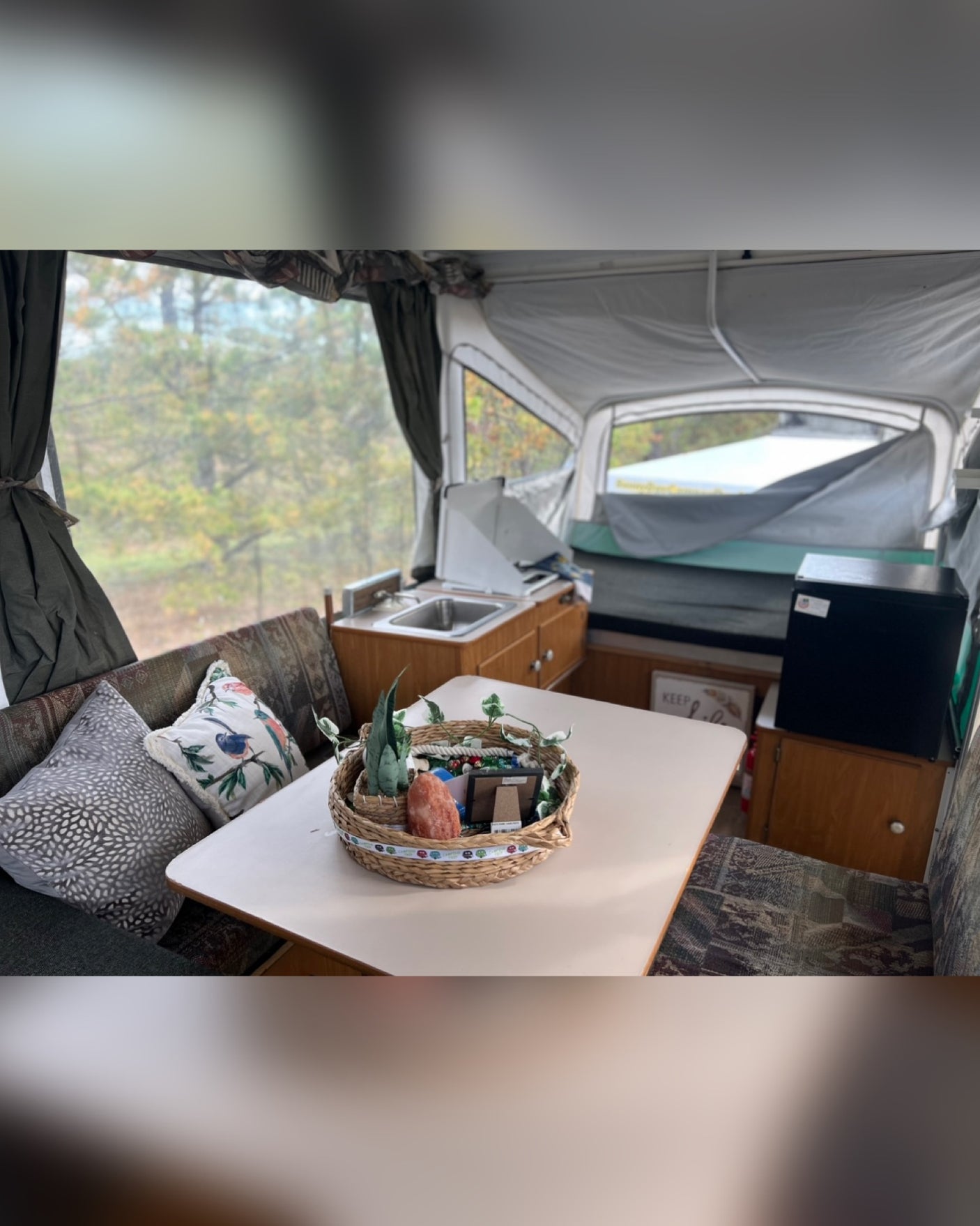 Experience comfortable camping in this RV rental! Pop-up camper interior features dining, kitchen, and scenic views.