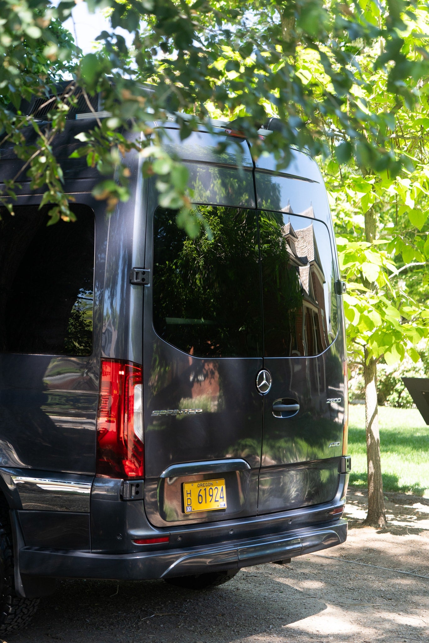 Dark grey Mercedes-Benz Sprinter van, Oregon plate H 61924, seen from rear under trees. Perfect RV rental for adventure. — photo 6