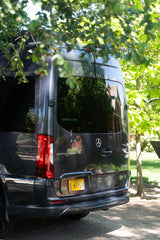 Dark grey Mercedes-Benz Sprinter van, Oregon plate H 61924, seen from rear under trees. Perfect RV rental for adventure.