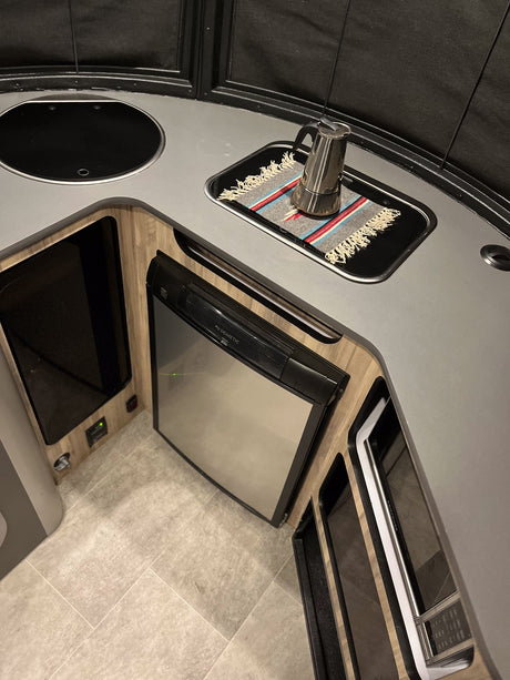 RV rental kitchen: Features a modern design with sink, covered cooktop, Dometic fridge, and Contoure microwave.
