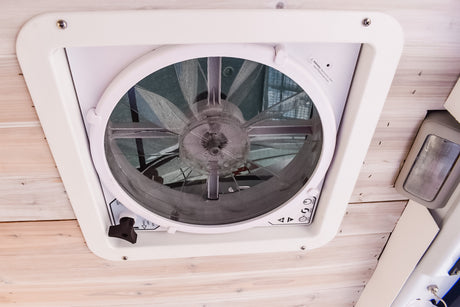 RV rental fan: Overhead view of a white ceiling fan, crucial for ventilation & comfort in your camper van.