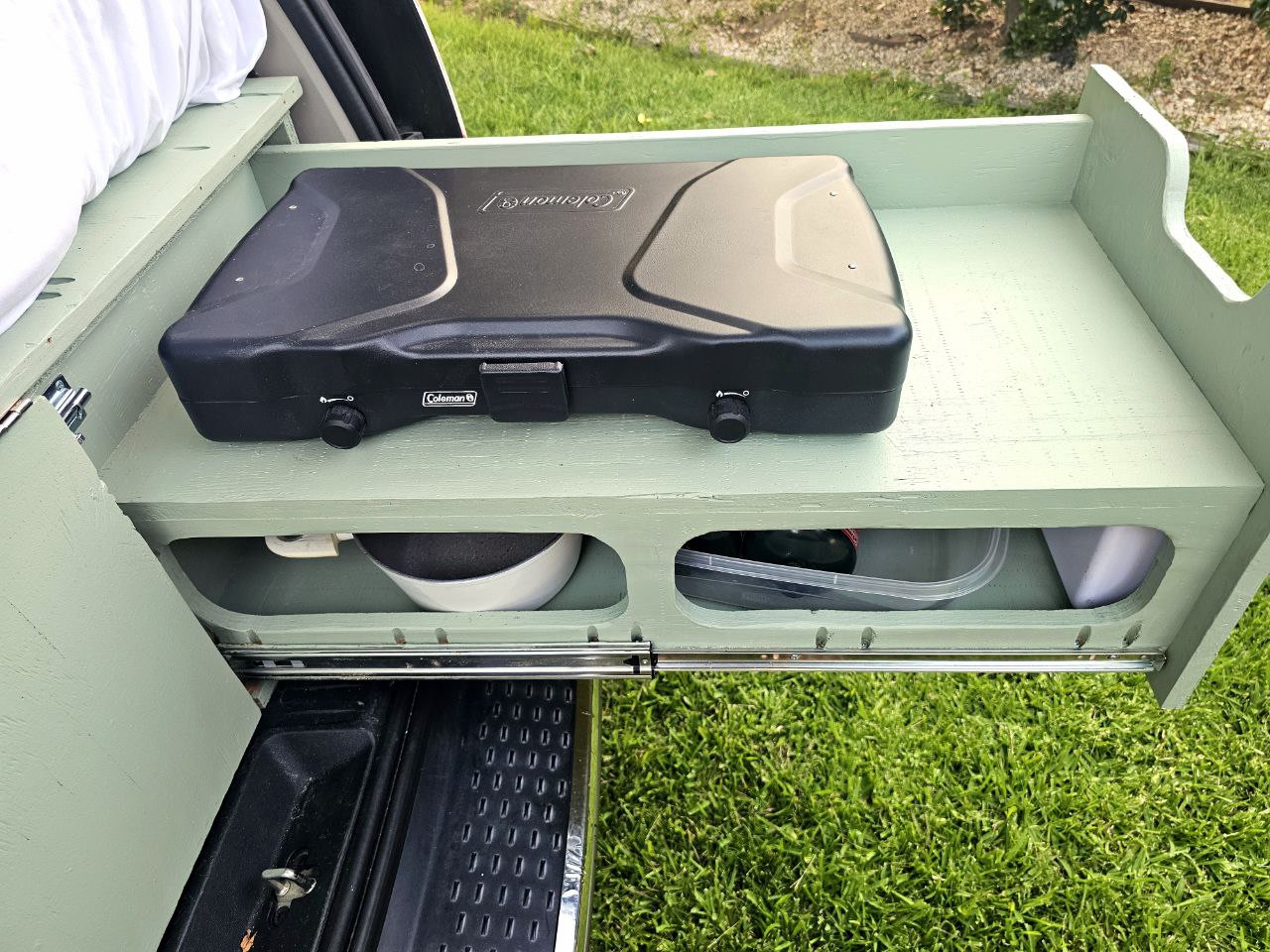 This RV rental features a pull-out camping kitchen with a Coleman stove, pan, and containers, ideal for outdoor cooking. — photo 7