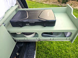 This RV rental features a pull-out camping kitchen with a Coleman stove, pan, and containers, ideal for outdoor cooking.
