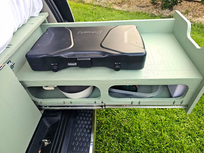 This RV rental features a pull-out camping kitchen with a Coleman stove, pan, and containers, ideal for outdoor cooking. — photo 7