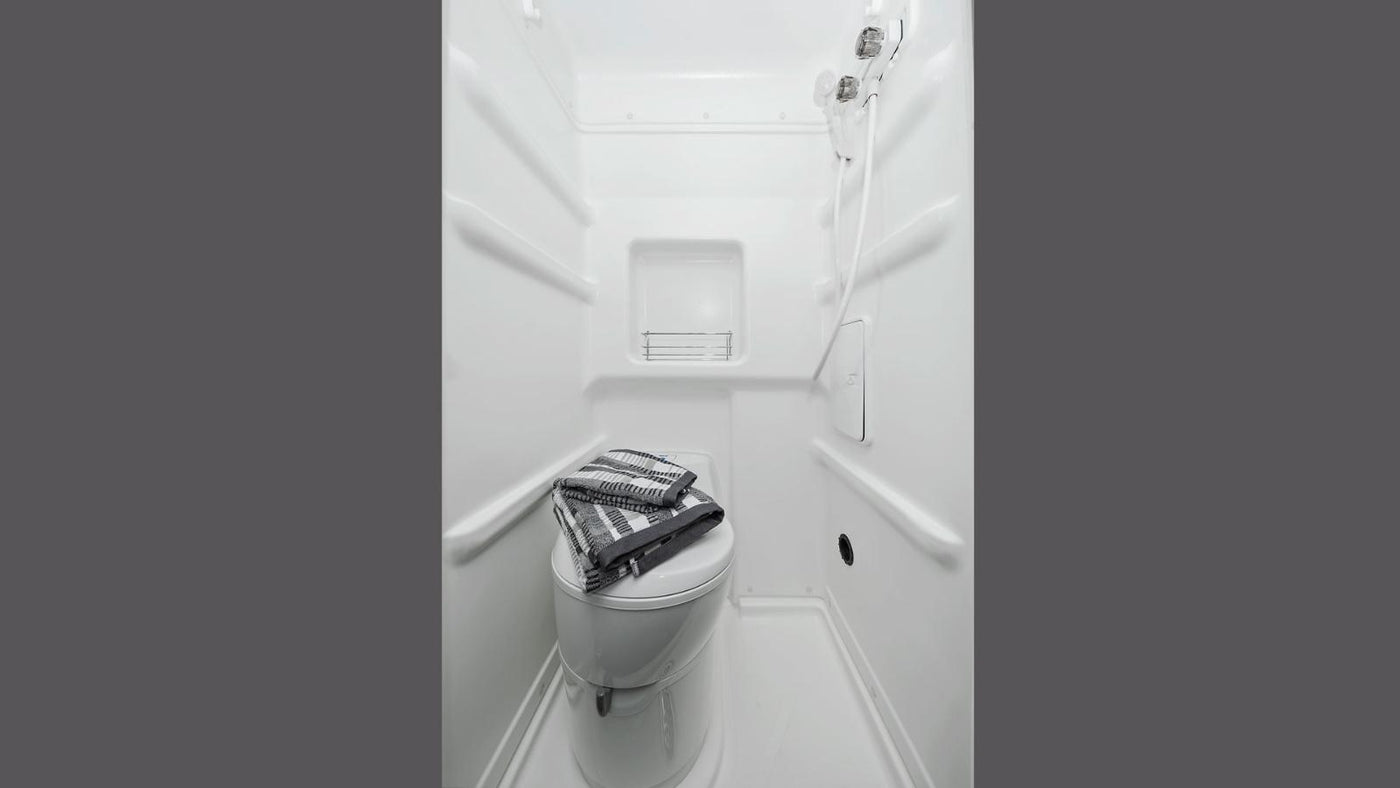 Compact RV rental wet bath with toilet and shower, featuring towels on the toilet. Ideal for camper travel. — photo 14