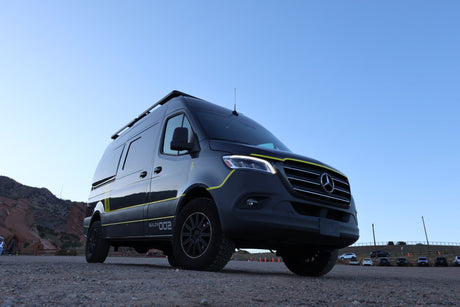 This sleek black Mercedes Sprinter rv rental van, "BUILD# 002", is parked at Red Rocks, ready for your next adventure.
